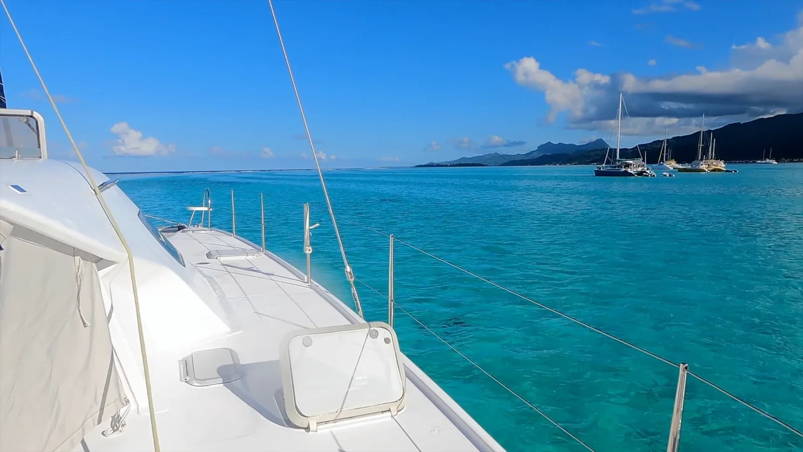 Une eau turquoise et des voiliers vus depuis le pont d’un bateau